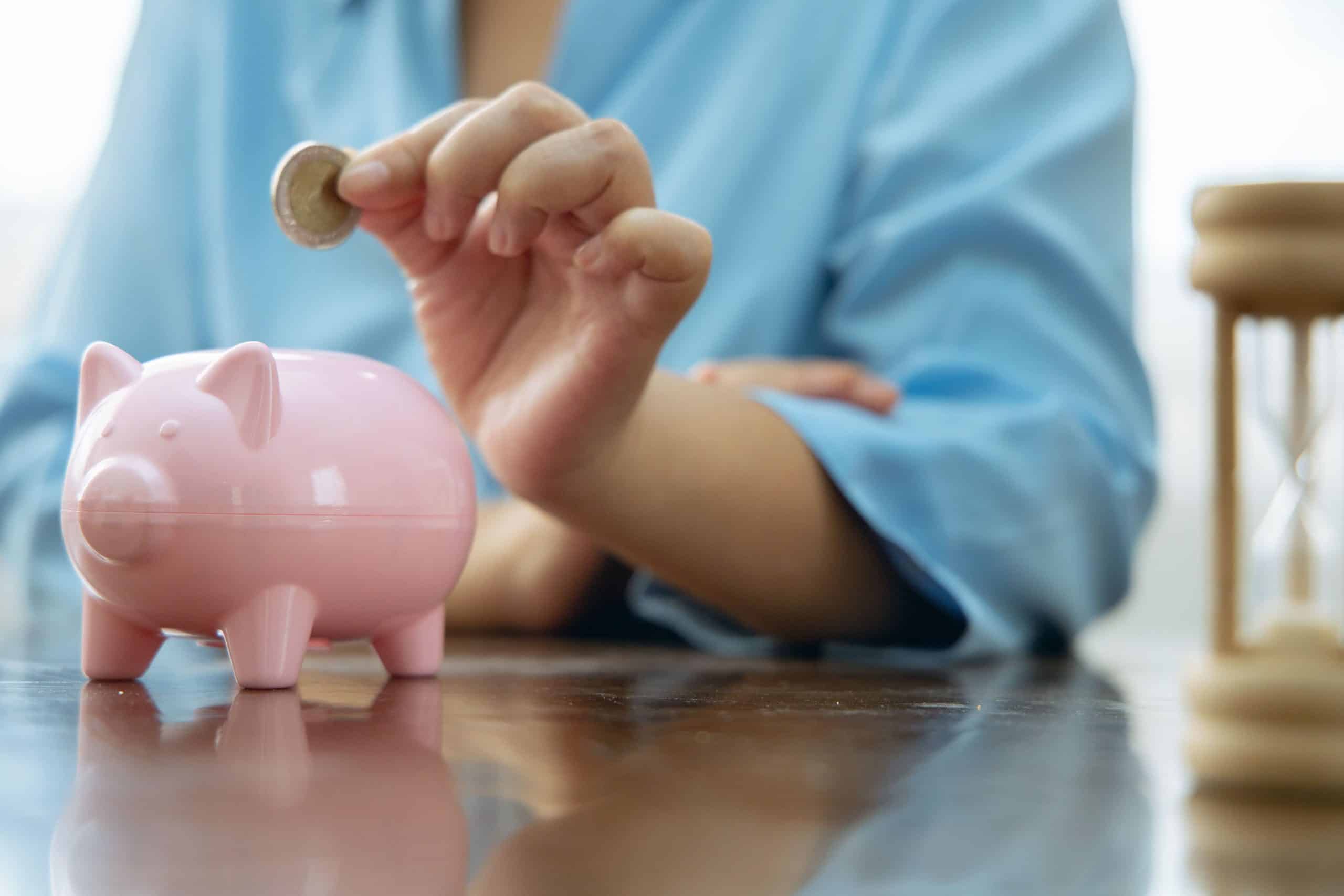 節約して浮いたお金を貯金箱にいれる女性の画像